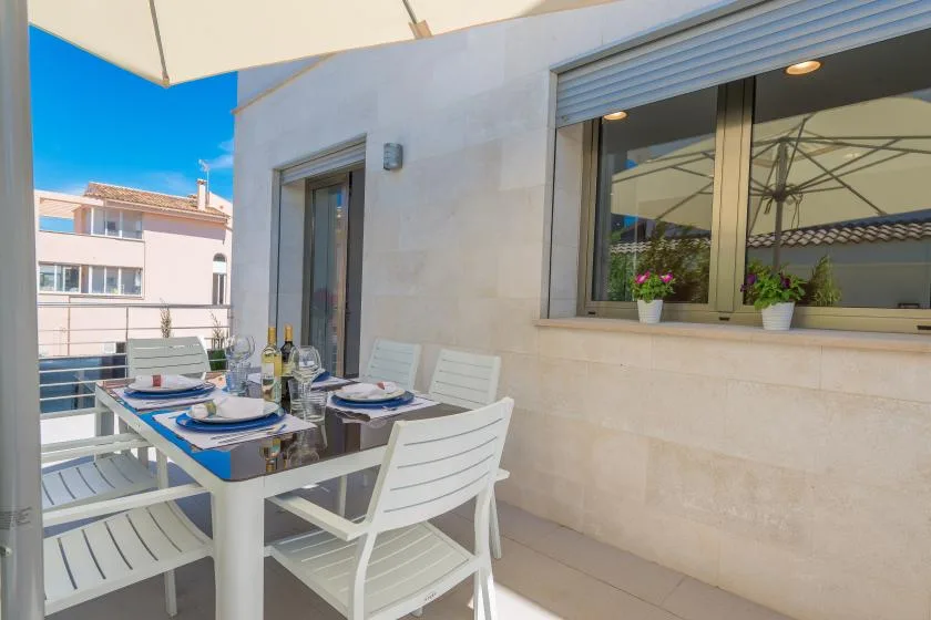 A balcony dining area with a table and white seating beside a large window.
