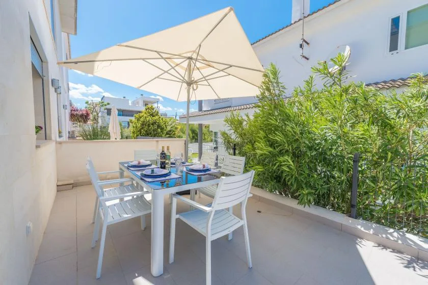 An outdoor dining area with a table and chairs beneath a large umbrella.