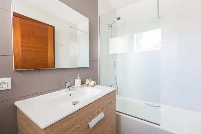 A modern bathroom with a wide sink, wall mirror, and glass shower.