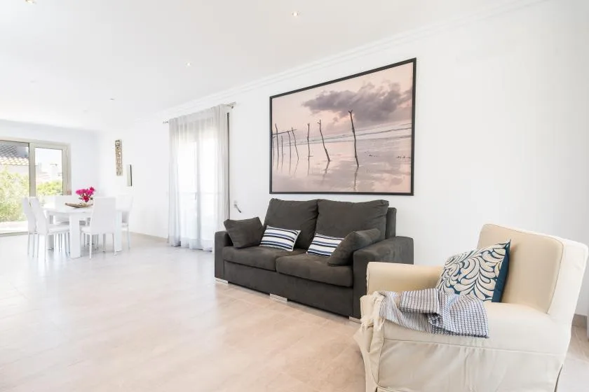 A bright living room with seating beneath a large framed beach photograph.