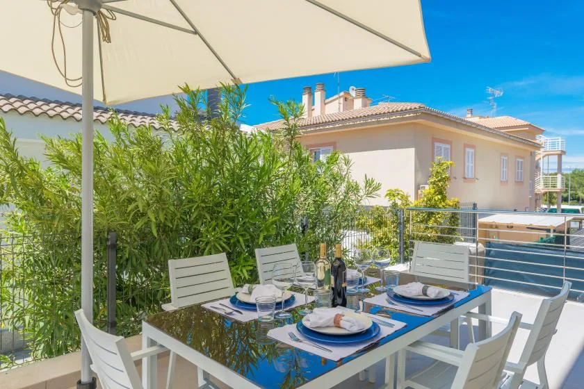 An outdoor dining area with a table and chairs beneath a large umbrella.