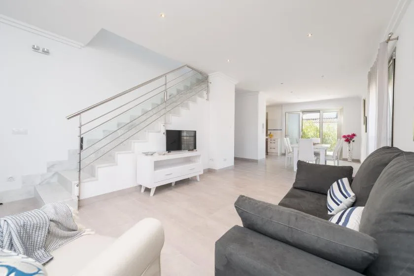 A bright living room with a staircase, television, and seating.