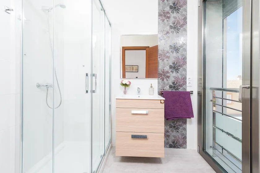 A bright bathroom with a vanity beside a glass shower.