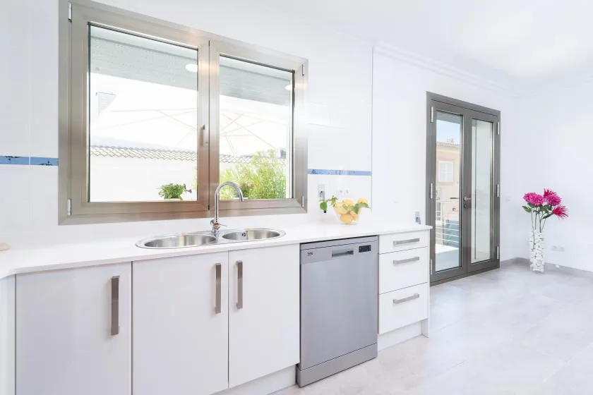 A bright kitchen with white cabinets, a sink, and a window.