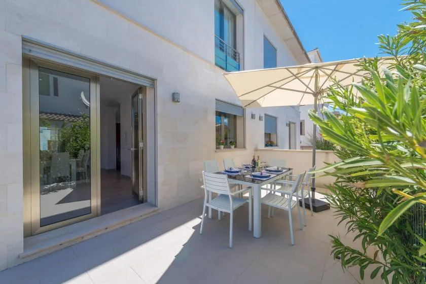 A sunny outdoor dining area beside a house, with a table under a large umbrella.