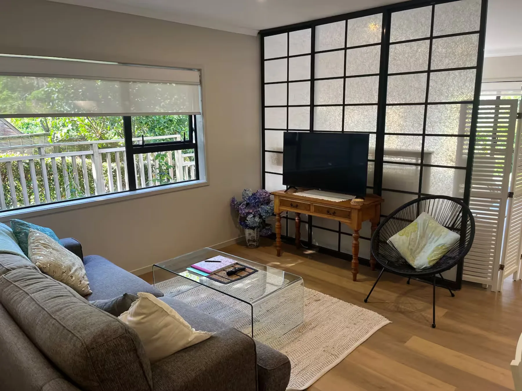 A living room with a television, seating, and large windows.