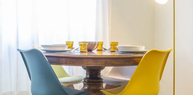 Una mesa de comedor está puesta con platos y rodeada de asientos azules y amarillos.