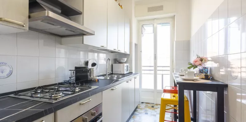 Una cocina estrecha con una encimera larga, estufa y puertas de vidrio luminosas.