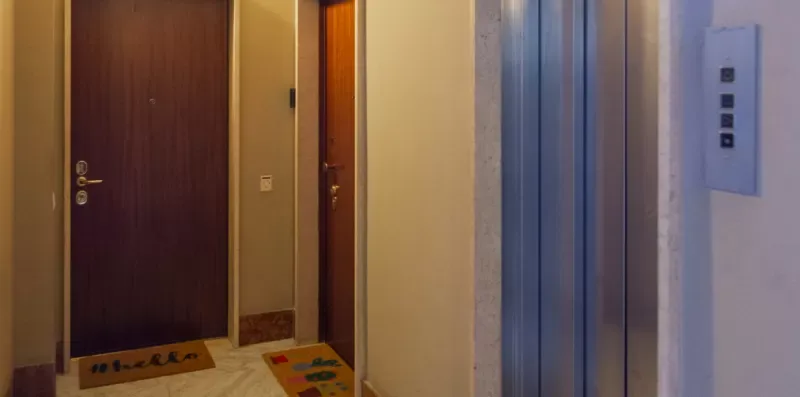 Un pasillo interior con puertas de madera junto a un ascensor metálico.