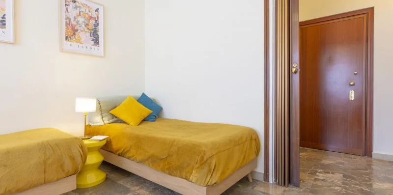 Un dormitorio con dos camas cubiertas con ropa de cama amarilla y una mesita de noche.