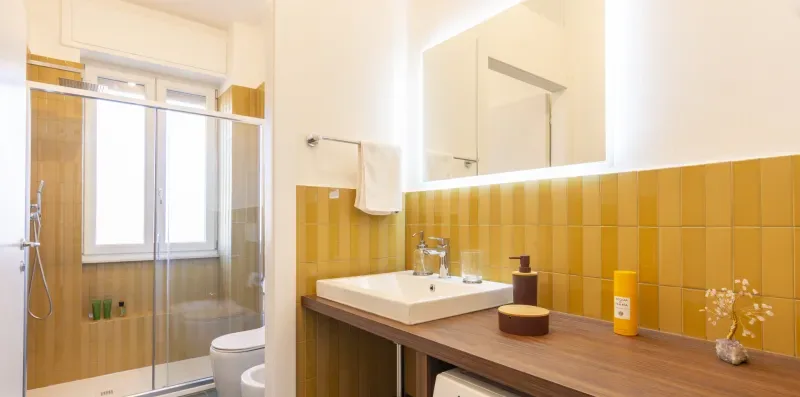 Un baño con ducha de vidrio, lavabo y encimera de madera.