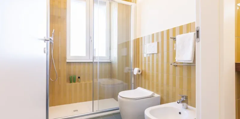 Un baño con ducha de vidrio, inodoro y lavabo.