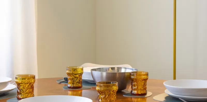 Una mesa de comedor está puesta con platos, cuencos y vasos.