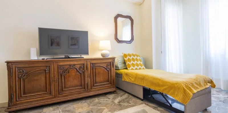 Un dormitorio con una cama individual, un televisor y un mueble de madera.