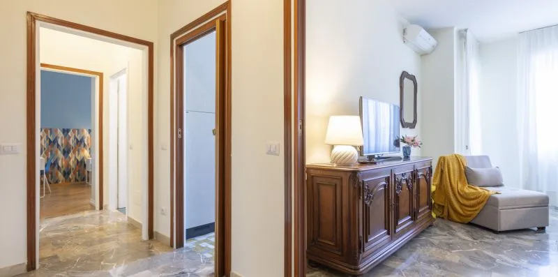 Una sala de estar con un mueble de madera, televisor y asientos junto a una ventana con cortinas.