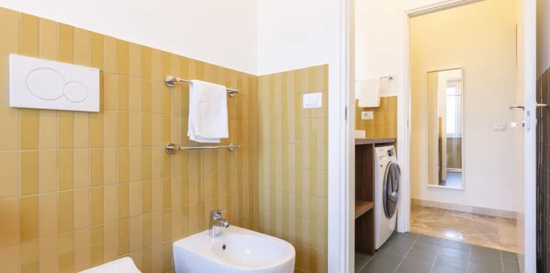 Un baño con un lavabo de pared y un toallero junto a la ducha.