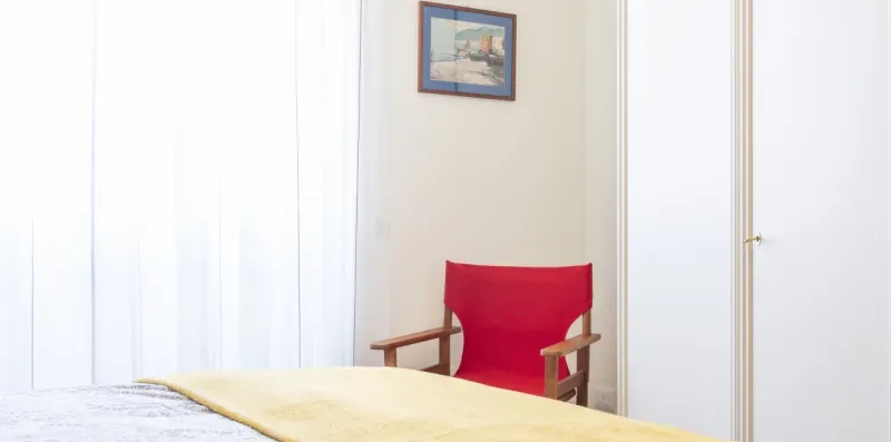 Una habitación luminosa con un sillón rojo y una mesa en primer plano.