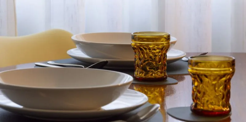 Una mesa está puesta con cuencos, platos y vasos de color ámbar.