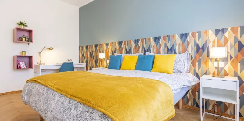Un dormitorio con una cama vestida con ropa de cama amarilla y azul.