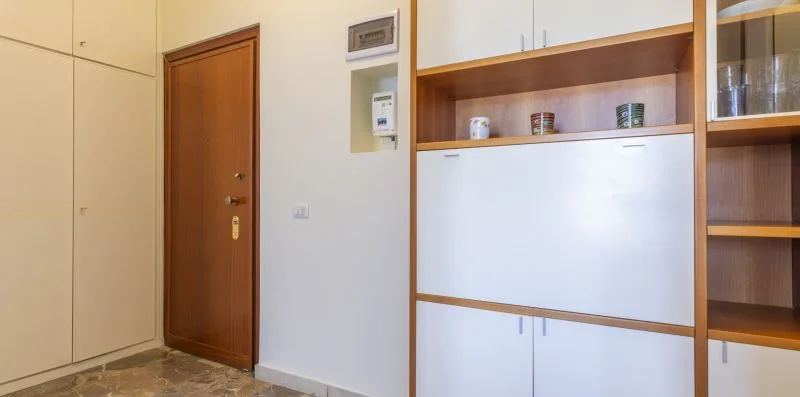 Un armario empotrado con estantes abiertos y una puerta de entrada de madera.