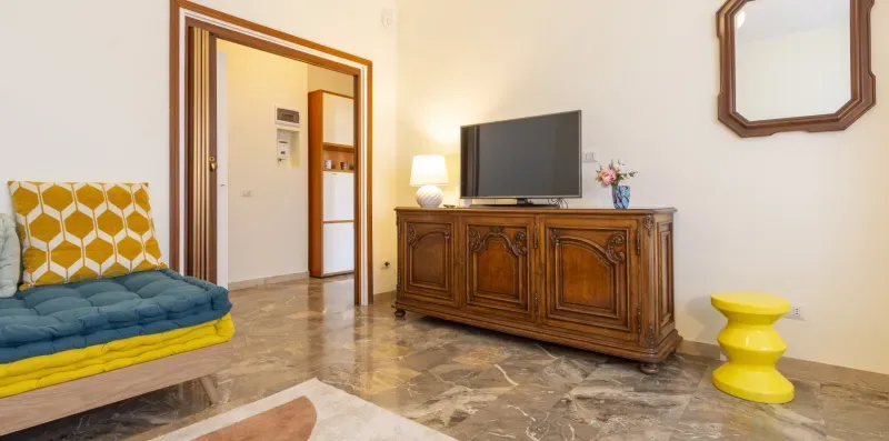 Una sala de estar con un televisor sobre un mueble de madera y asientos coloridos.