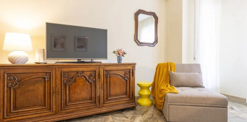 Una zona de estar tiene un mueble de madera tallada, un televisor y asientos tapizados.