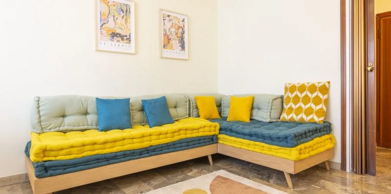 Una sala de estar con asientos en forma de L y cojines coloridos.