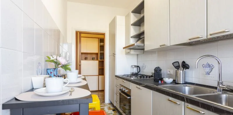 Una cocina estrecha con encimera, fregadero, estufa y armarios.