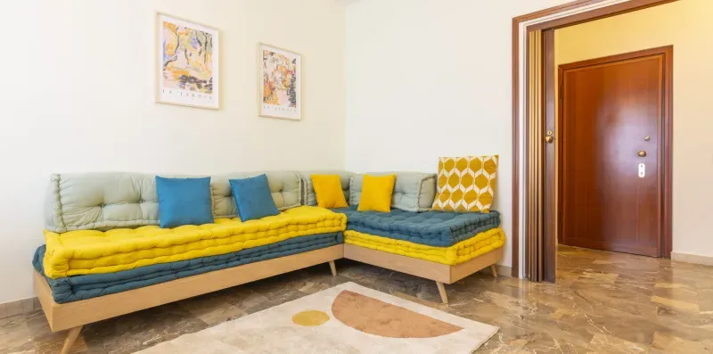 Una sala de estar tiene un asiento esquinero con cojines de colores.