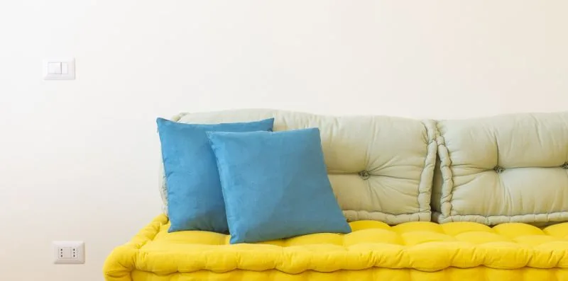 Una zona de asientos acolchada con cojines azules junto a una pared lisa.