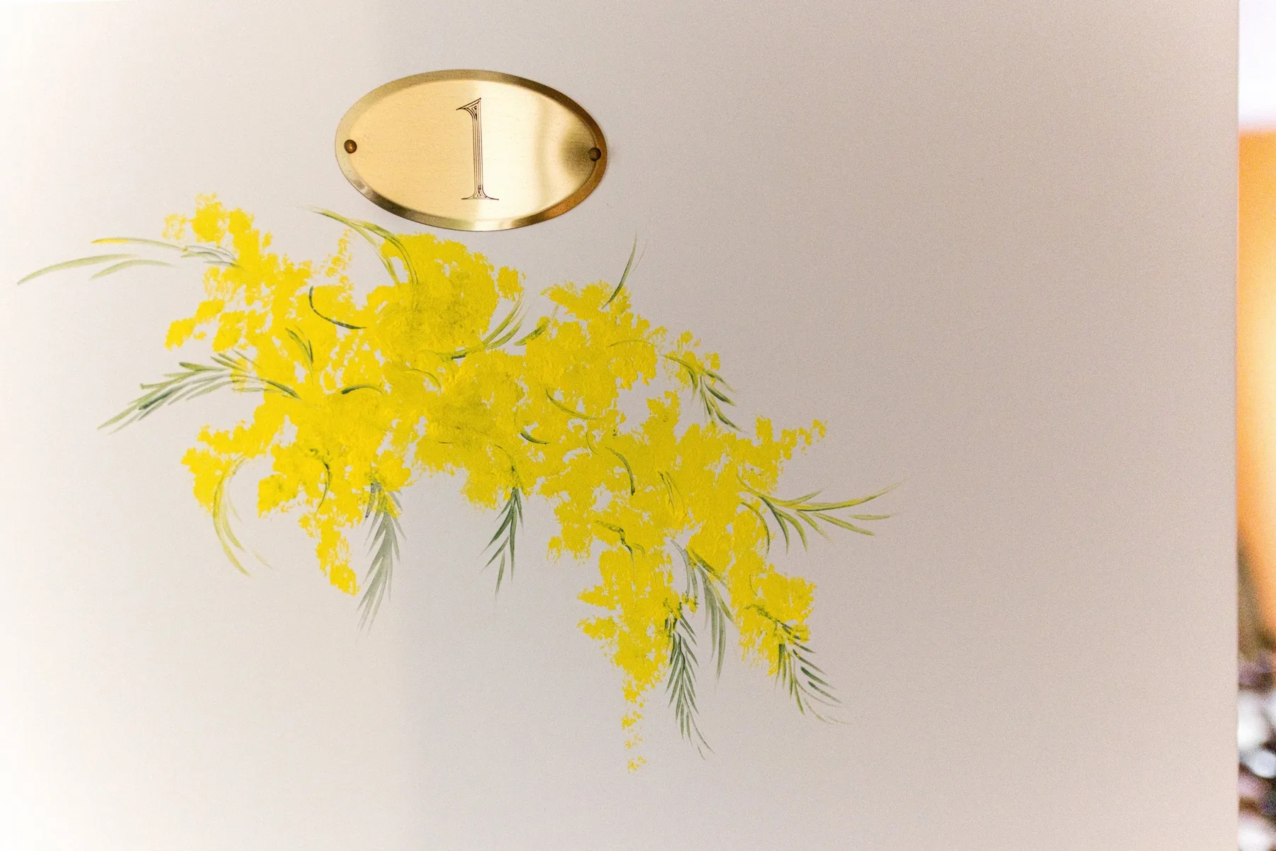 A wall plaque marked with the number one hangs above a spray of yellow flowers.