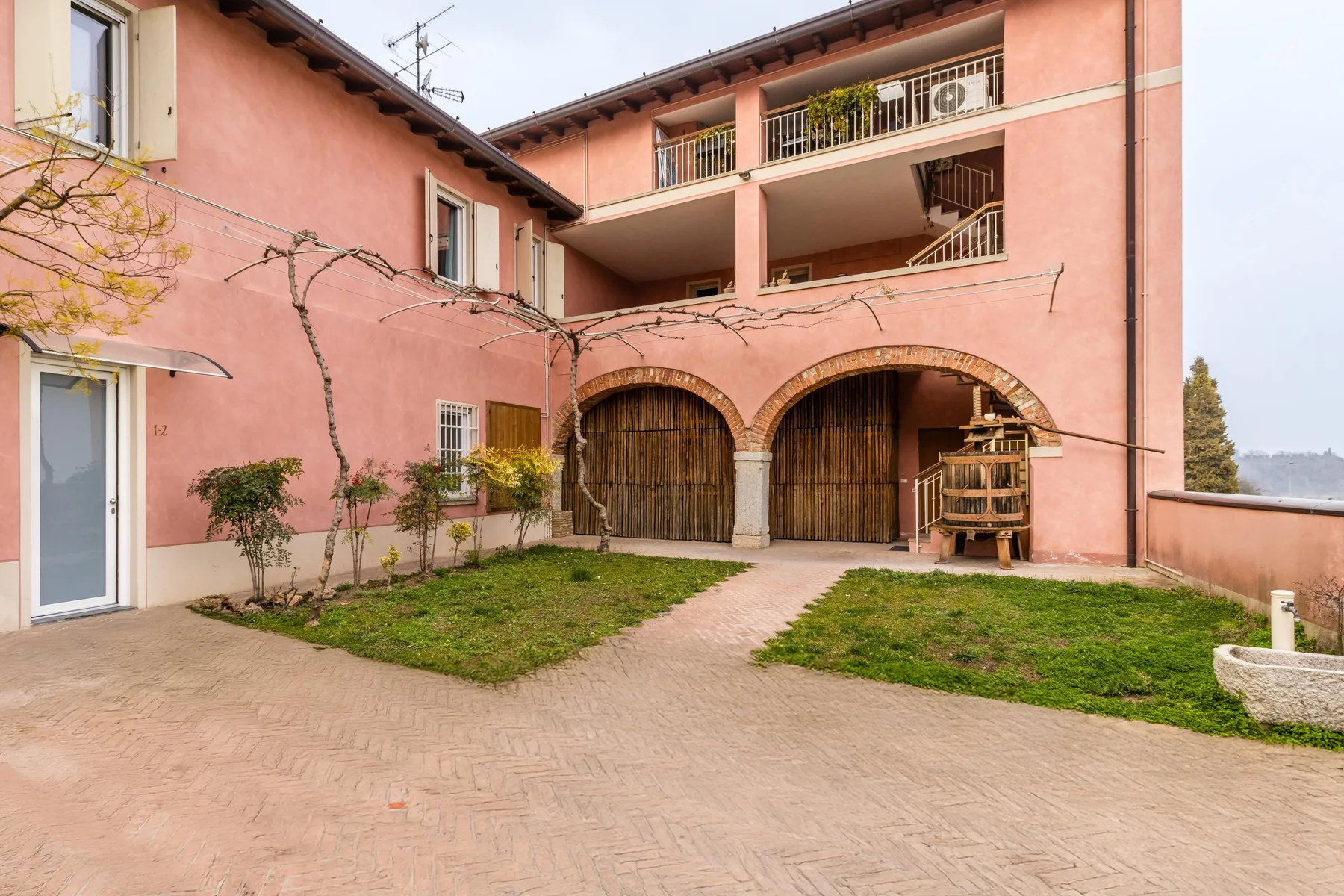 A pink courtyard building with arched wooden gates and an upper balcony.