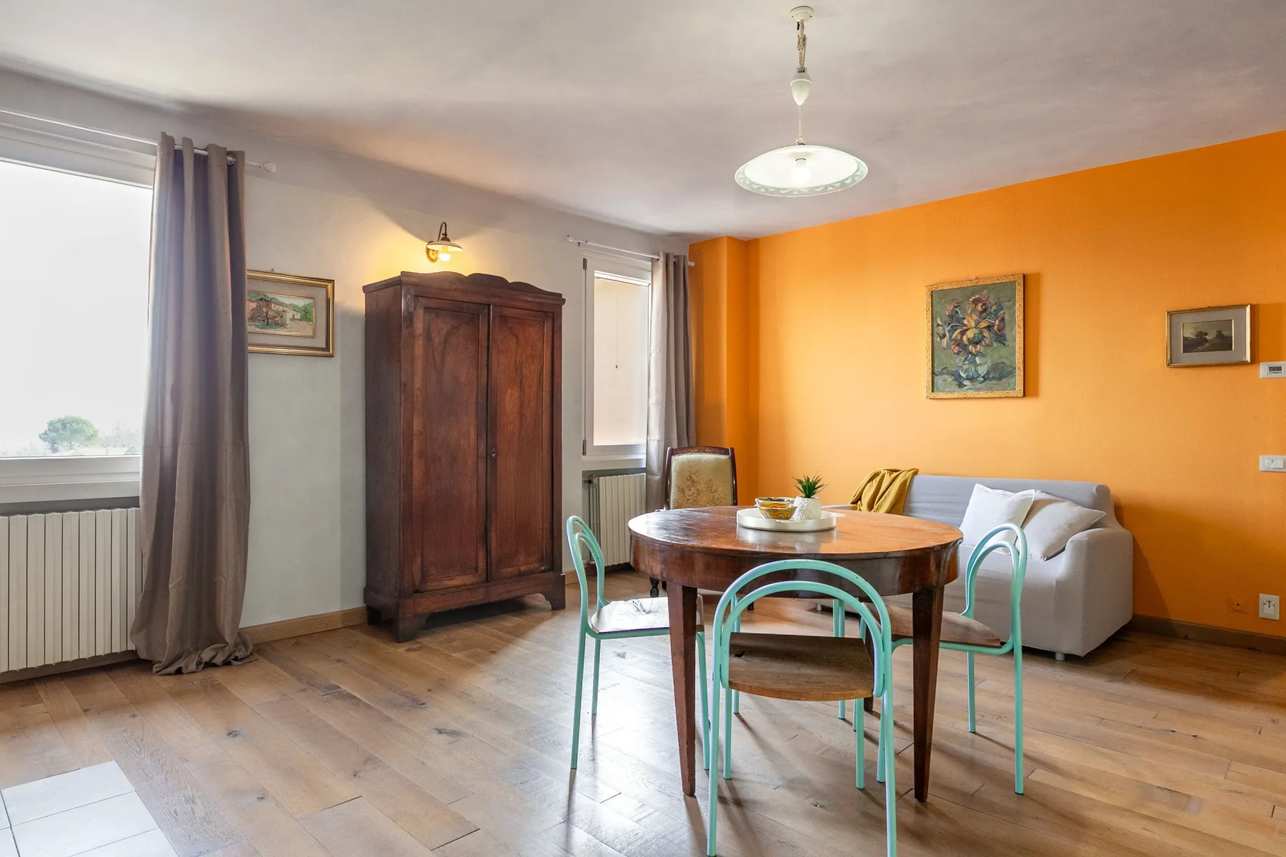 A dining area with a round table and seating beside an orange wall.