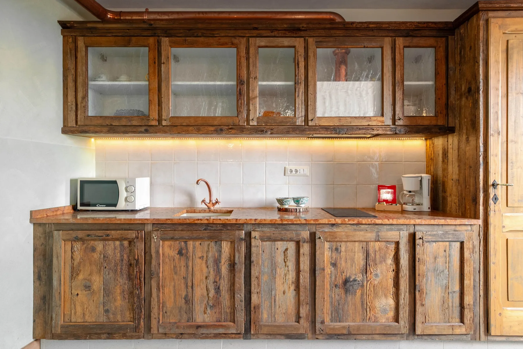A rustic kitchen with wooden cabinets, a countertop, and small appliances.