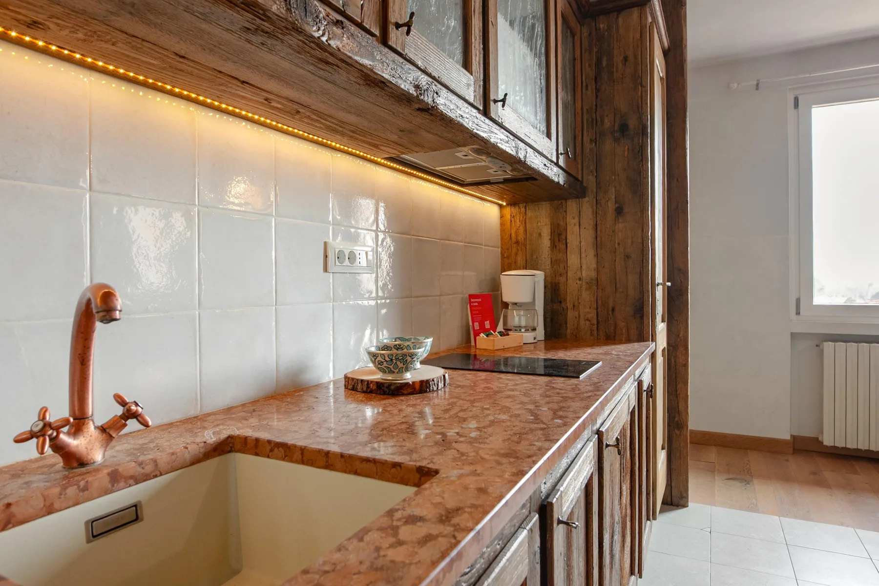 A kitchen counter with a sink, tiled backsplash, and wooden cabinets.