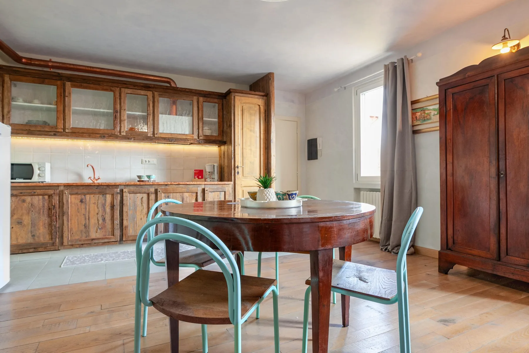 A dining area with a round wooden table and chairs beside a kitchen.