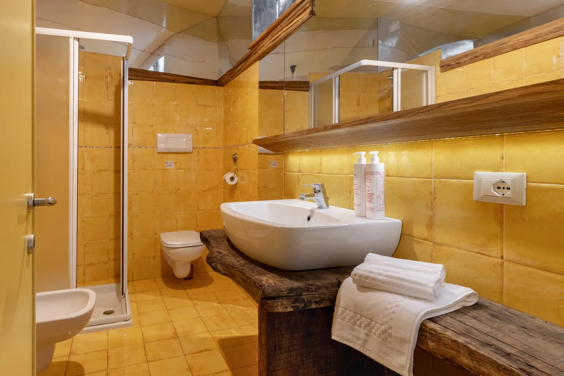 A tiled bathroom with a sink, mirror, and glass shower.