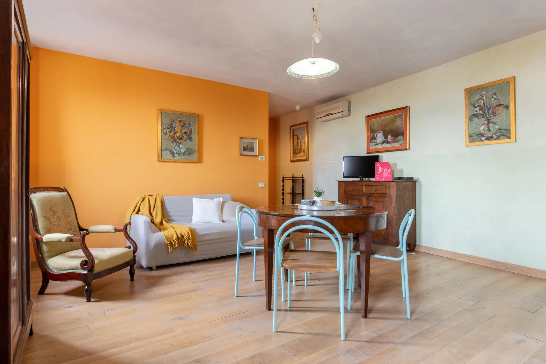 A living and dining room with a sofa, table, and wall art.