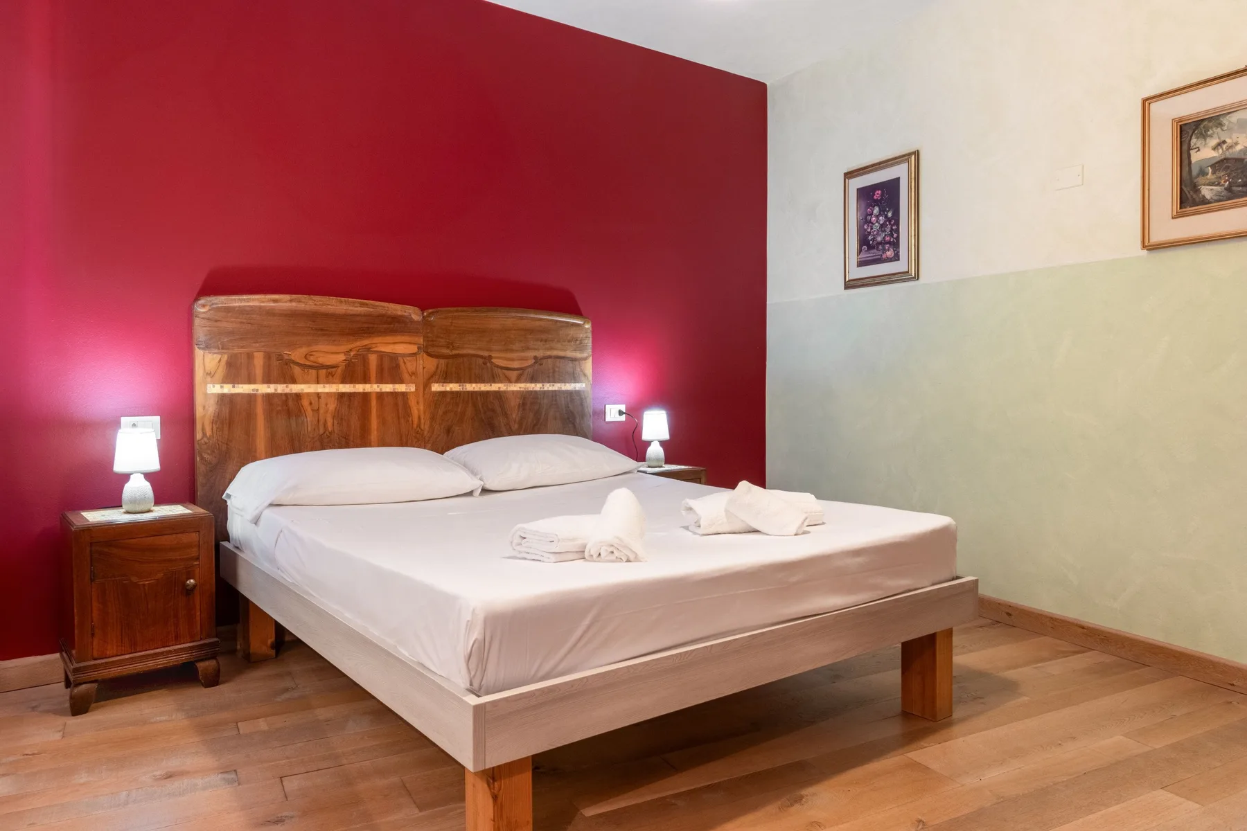 Bedroom with a bed against a red accent wall.