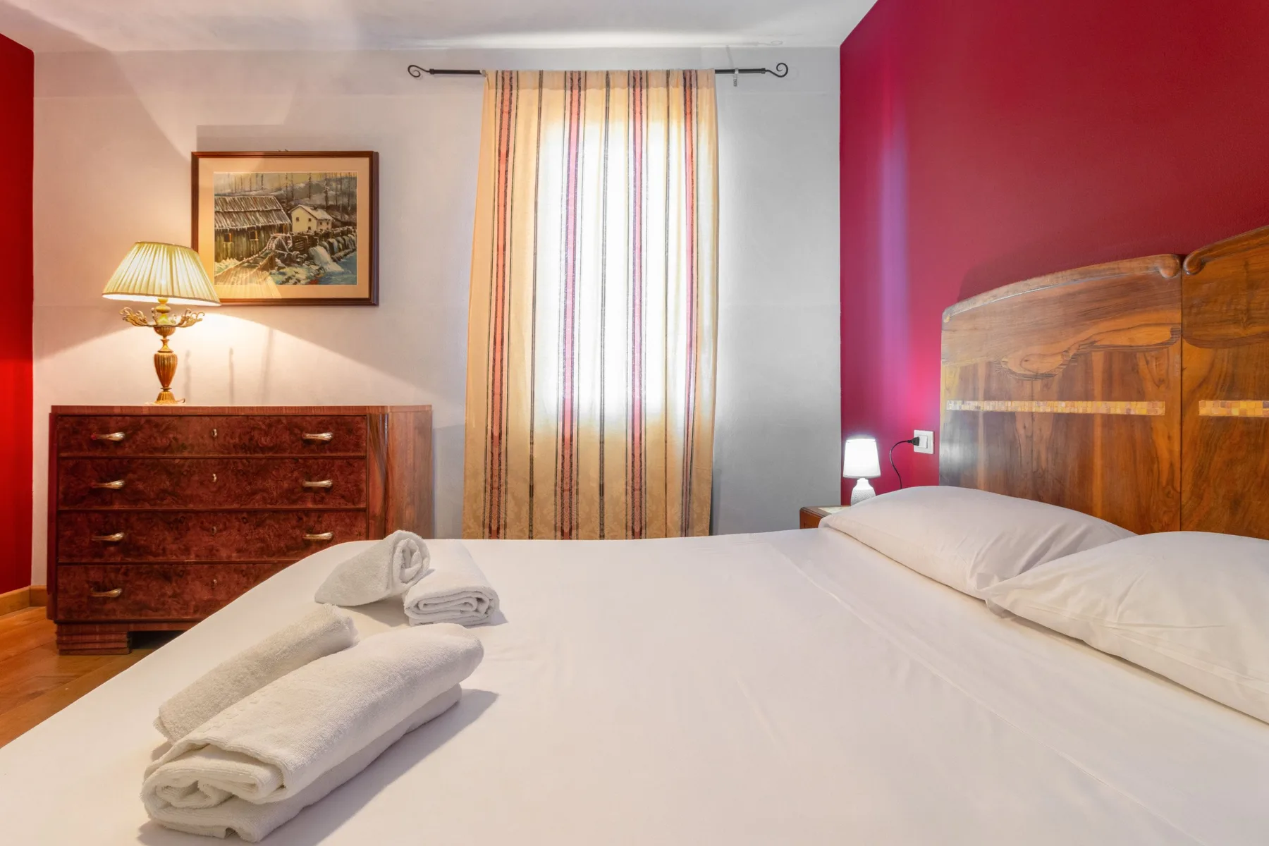 A bedroom with a bed, folded towels, and striped curtains.