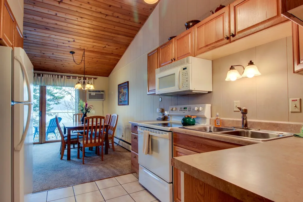 A kitchen and dining area with wooden cabinets and a table by the sliding glass doors.