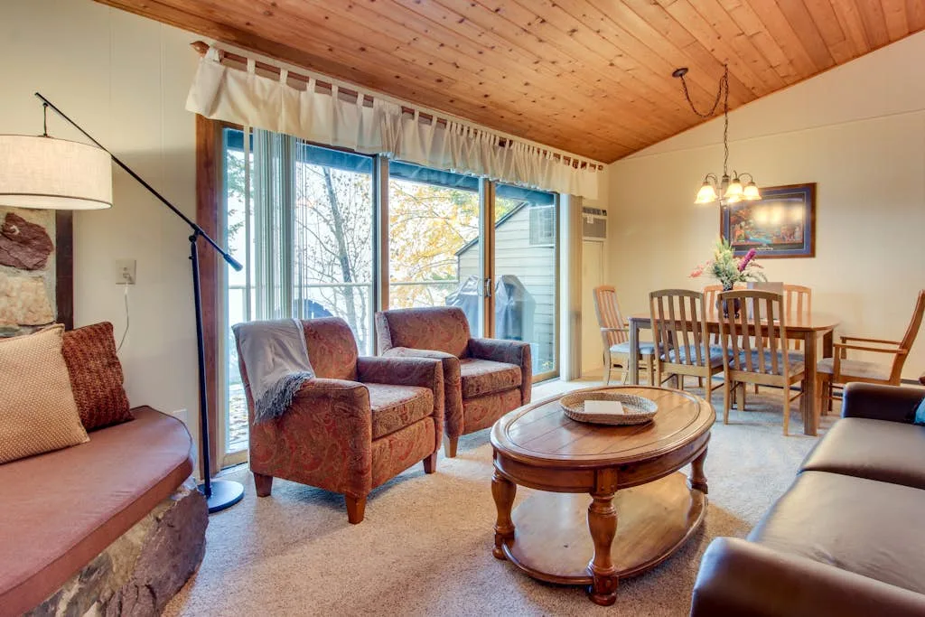 A living room with seating beside large windows and a dining table.
