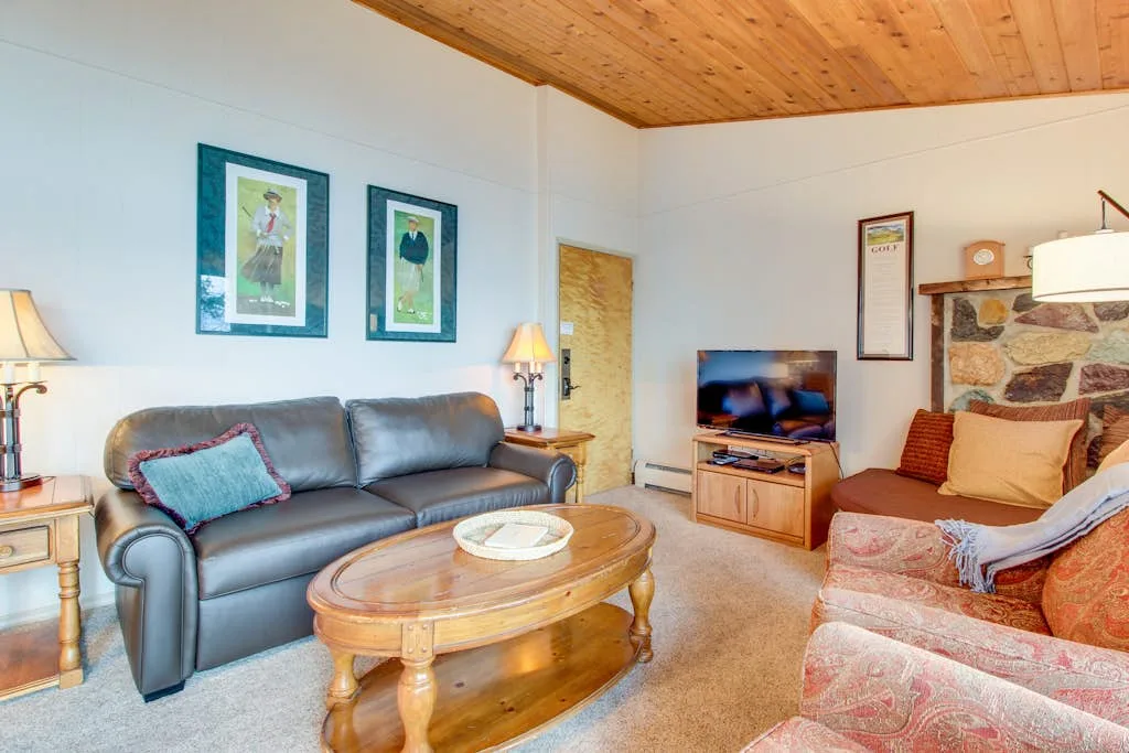 A living room with seating, a wooden coffee table, and a television.