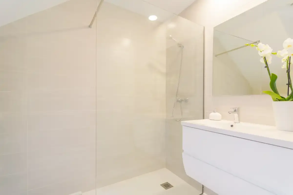 Un baño luminoso con ducha y un mueble de lavabo blanco.