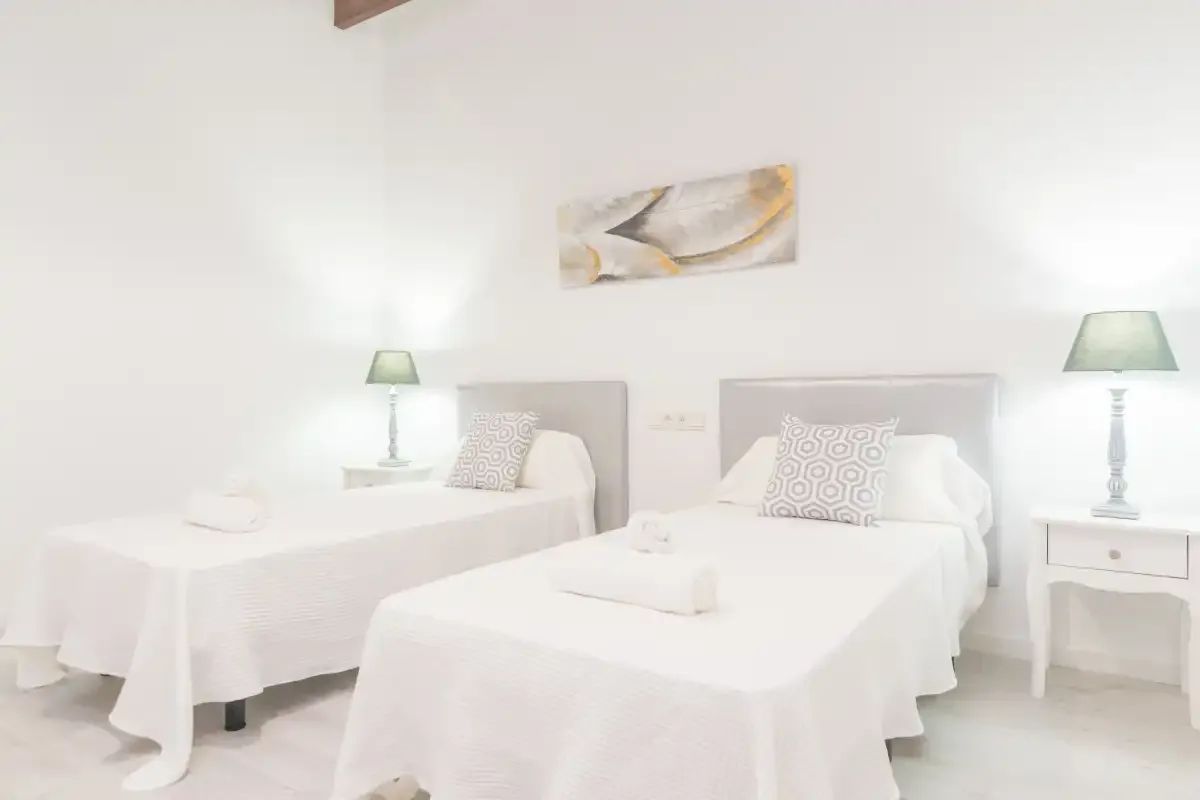Un dormitorio luminoso con dos camas y mesitas de noche a juego.