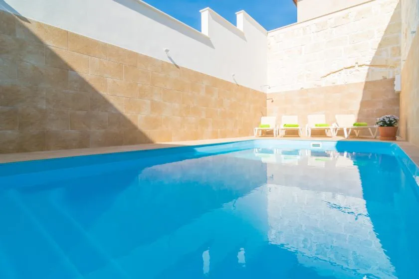 Una piscina está junto a paredes altas y una fila de asientos de descanso.