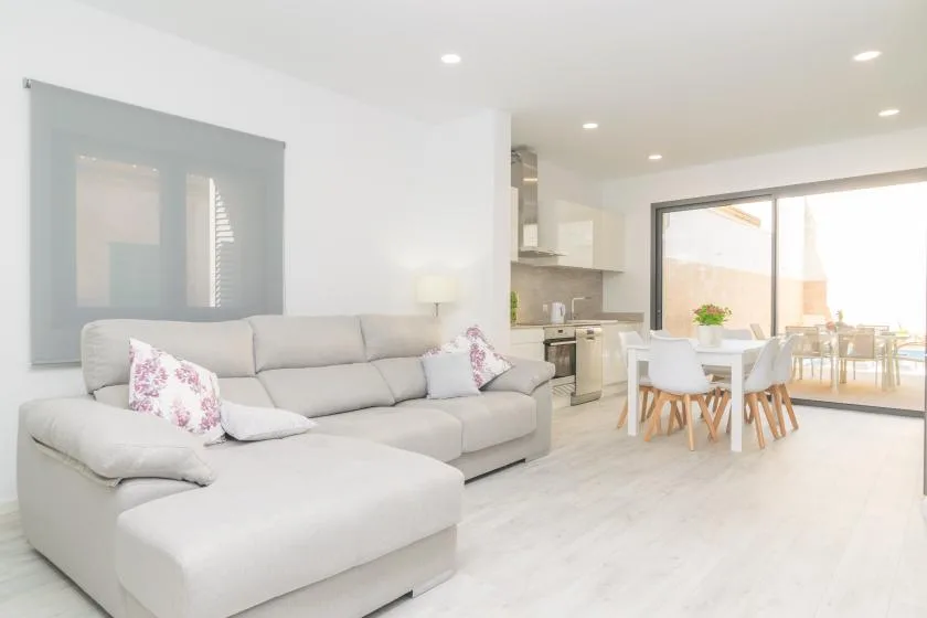 Una luminosa sala-comedor de concepto abierto con sofá seccional y cocina.
