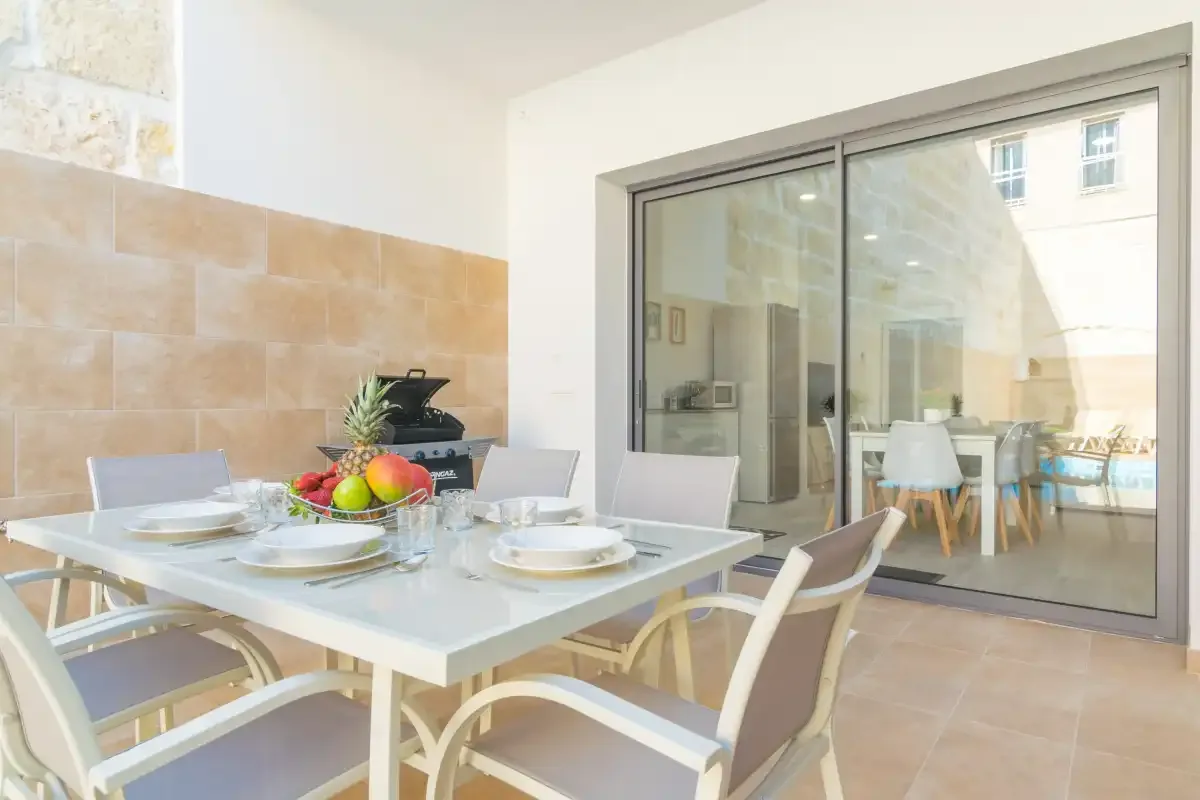 Comedor con la mesa puesta junto a grandes puertas correderas de cristal.