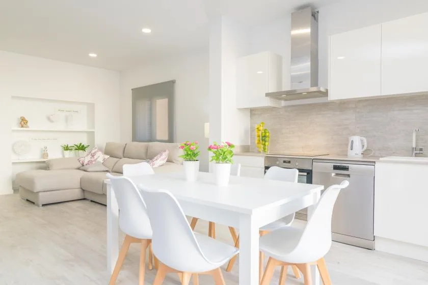 Una luminosa sala de estar y comedor de planta abierta con mesa blanca y asientos.