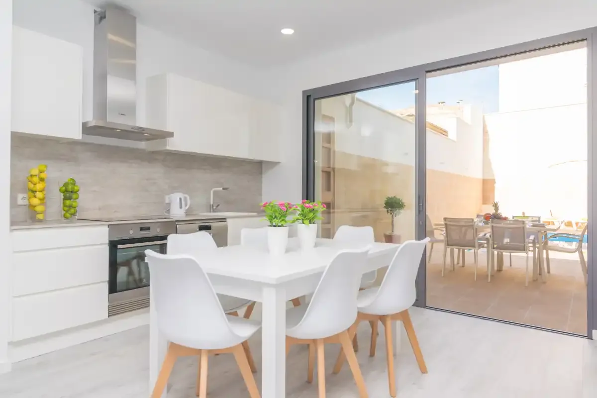 Una cocina luminosa con comedor se abre a un patio con asientos al aire libre.